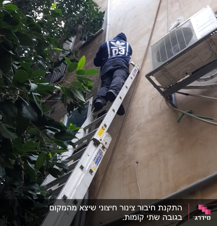 אדם על סולם ליד צינור חיצוני על קיר